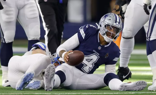 Dallas Cowboys quarterback Dak Prescott (4) recovers from being sacked by Detroit Lions defensive end Aidan Hutchinson, left, in the second half of an NFL football game in Arlington, Texas, Sunday, Oct. 13, 2024. (AP Photo/Gareth Patterson)