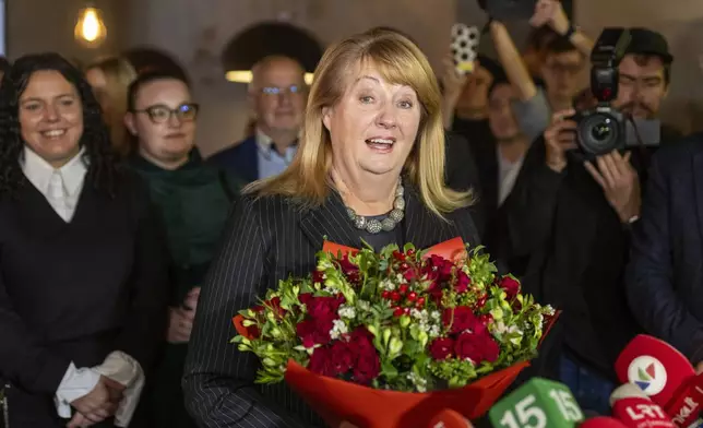 Leader of the Social Democratic Party Vilija Blinkeviciute, center, smiles as she waits for the results of the second round of Lithuania's parliamentary election, in an office in Vilnius, Lithuania, Sunday, Oct. 27, 2024. (AP Photo/Mindaugas Kulbis)