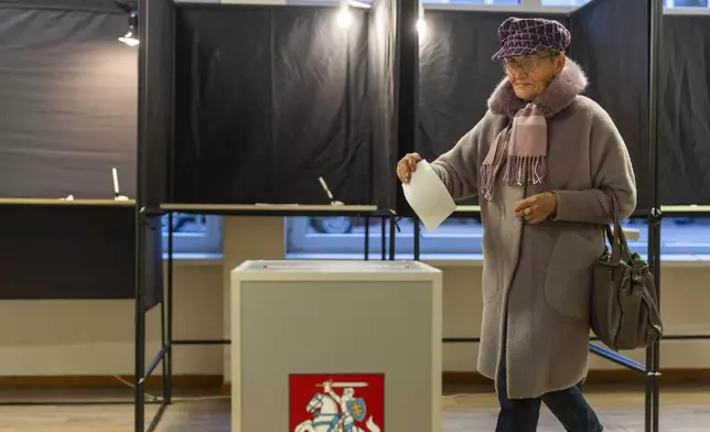 A local resident walks to cast their ballots at a polling station during a second round of voting in parliamentary election, in Vilnius, Lithuania, Sunday, Oct. 27, 2024. (AP Photo/Mindaugas Kulbis)