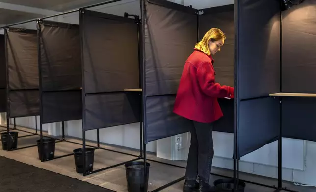 A local resident fills ballots at a polling station during the second round of voting in parliamentary election, in Vilnius, Lithuania, Tuesday, Oct. 22, 2024. (AP Photo/Mindaugas Kulbis)