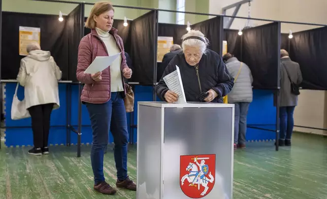 An elderly woman casts her vote at the polling station during the first round of voting in parliamentary elections, in Vilnius, Lithuania, Sunday, Oct. 13, 2024. (AP Photo/Mindaugas Kulbis)