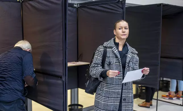 A woman leaves the polling booth at the polling station during the advance voting in the first round of a parliamentary election in Vilnius, Lithuania, Wednesday, Oct. 9, 2024. (AP Photo/Mindaugas Kulbis)