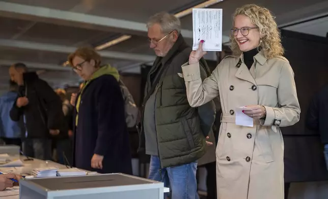 Freedom Party leader Ausrine Armonaite prepares to cast his ballot at a polling station during the advance voting in the first round of a parliamentary election in Vilnius, Lithuania, Wednesday, Oct. 9, 2024. (AP Photo/Mindaugas Kulbis)