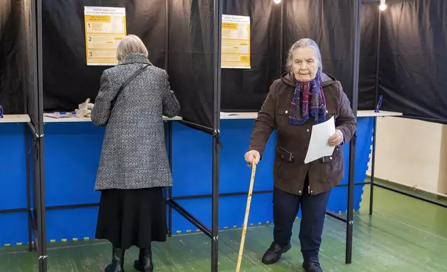 A woman leaves a polling booth at a polling station during the first round of voting in a parliamentary election, in Vilnius, Lithuania, Sunday, Oct. 13, 2024. (AP Photo/Mindaugas Kulbis)