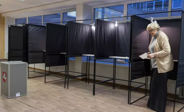 A woman leaves the polling booth at a polling station during the second round of voting in parliamentary election, in Vilnius, Lithuania, Sunday, Oct. 27, 2024. (AP Photo/Mindaugas Kulbis)