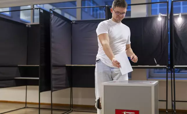 A man casts his ballot at a polling station during a second round of voting in parliamentary election, in Vilnius, Lithuania, Sunday, Oct. 27, 2024. (AP Photo/Mindaugas Kulbis)