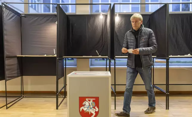 A local resident walks to cast their ballots at a polling station during a second round of voting in parliamentary election, in Vilnius, Lithuania, Sunday, Oct. 27, 2024. (AP Photo/Mindaugas Kulbis)