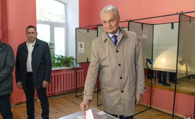 Lithuania's President Gitanas Nauseda prepares to cast his ballot at a polling station during a second round of voting in parliamentary election, in Vilnius, Lithuania, Sunday, Oct. 27, 2024. (AP Photo/Mindaugas Kulbis)