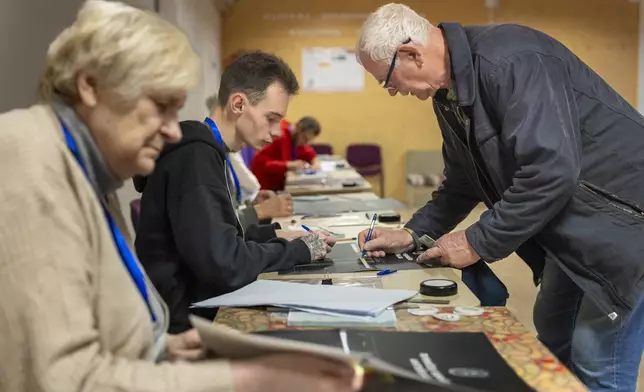 A voter arrives at a polling station during a second round of voting in parliamentary election, in Vilnius, Lithuania, Sunday, Oct. 27, 2024. (AP Photo/Mindaugas Kulbis)