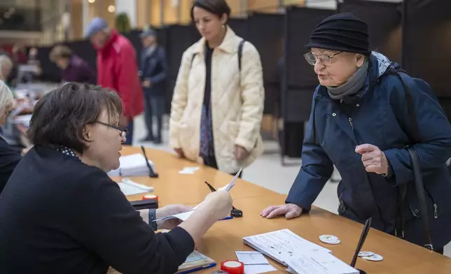 A woman arrives at a polling station during the advance voting in the first round of a parliamentary election in Vilnius, Lithuania, Wednesday, Oct. 9, 2024. (AP Photo/Mindaugas Kulbis)