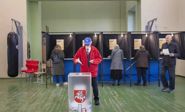 Local residents vote at a polling station during the first round of voting in a parliamentary election, in Vilnius, Lithuania, Sunday, Oct. 13, 2024. (AP Photo/Mindaugas Kulbis)