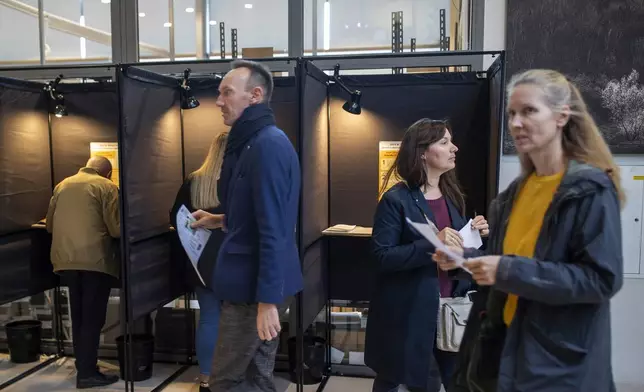 Local residents vote at the polling station during the advance voting in the first round of a parliamentary election in Vilnius, Lithuania, Wednesday, Oct. 9, 2024. (AP Photo/Mindaugas Kulbis)