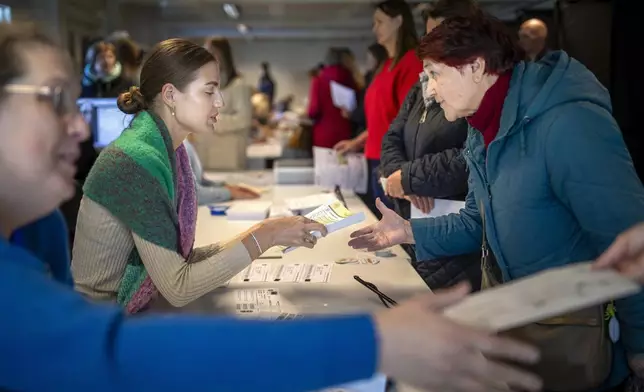 FILE - A woman arrives at a polling station during the advance parliamentary elections in Vilnius, Lithuania, Tuesday, Oct. 8, 2024. (AP Photo/Mindaugas Kulbis, File)