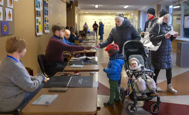 Local residents arrive to cast their ballots at a polling station during a second round of voting in parliamentary election, in Vilnius, Lithuania, Sunday, Oct. 27, 2024. (AP Photo/Mindaugas Kulbis)