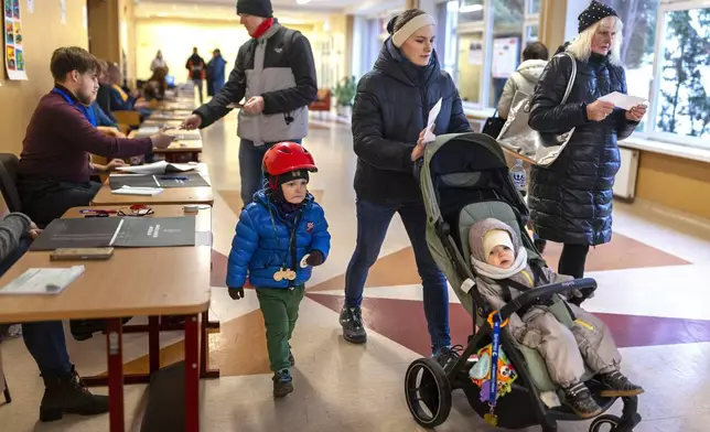 Local residents walk to cast their ballots at a polling station during a second round of voting in parliamentary election, in Vilnius, Lithuania, Sunday, Oct. 27, 2024. (AP Photo/Mindaugas Kulbis)