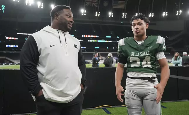 De La Salle High School coach and former NFL running back Maurice Jones-Drew, left, talks to his son Duece Jones-Drew, a running back ont he team after a football game between the NFL Academy team and De La Salle high school, Tuesday, Oct. 8, 2024, in London. (AP Photo/Kin Cheung)