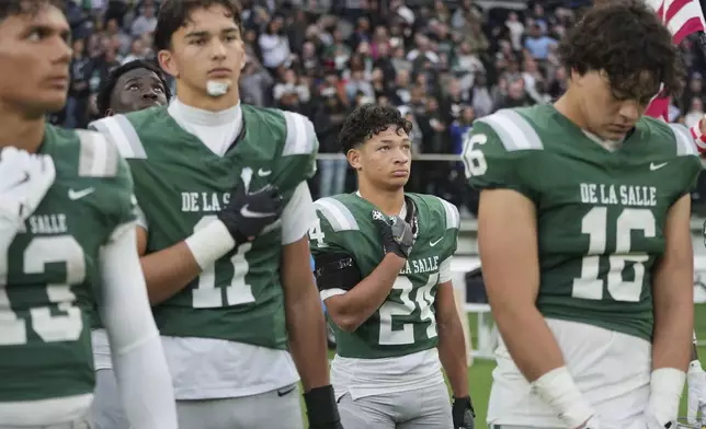 De La Salle running back Duece Jones-Drew second right, stands for the national anthem before a football game between the NFL Academy team and De La Salle High School, Tuesday, Oct. 8, 2024, in London. (AP Photo/Kin Cheung)