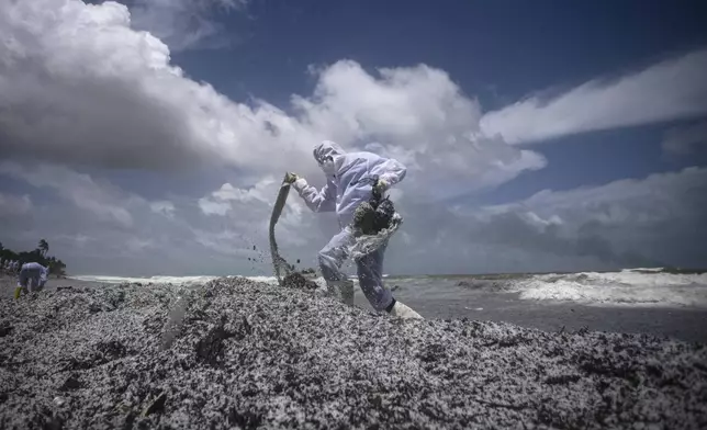 FILE - A Sri Lankan navy soldier wearing a protective suit walks on mounds of debris that washed ashore from the burning Singaporean ship X-Press Pearl which is anchored off Colombo port at Kapungoda, on the outskirts of Colombo, Sri Lanka, Thursday, May 27, 2021. (AP Photo/Eranga Jayawardena, File)