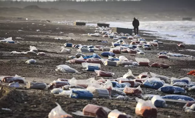 FILE - A person walks past detritus in the area between Tranum and Slette beach in Denmark, Saturday, Dec. 23, 2023, a day after a Maersk ship dropped 46 containers off the coast between Bulbjerg and Svinkloev in the northwestern part of Jutland, during storm Pia. (Claus Bjoern Larsen/Ritzau Scanpix via AP, File)