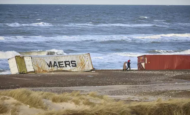 FILE - People walk past stranded containers in the area between Tranum and Slette beach in Denmark, Saturday, Dec. 23, 2023, a day after a Maersk ship dropped 46 containers off the coast between Bulbjerg and Svinkloev in the northwestern part of Jutland, during storm Pia. (Claus Bjoern Larsen/Ritzau Scanpix via AP, File)