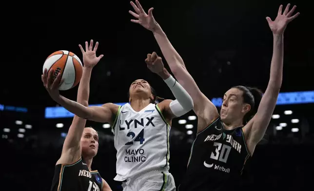 Minnesota Lynx's Napheesa Collier, center, attempts to score against New York Liberty's Leonie Fiebich, left, and Breanna Stewart, right during the second half in Game 1 of a WNBA basketball final playoff series, Thursday, Oct. 10, 2024, in New York. (AP Photo/Pamela Smith)