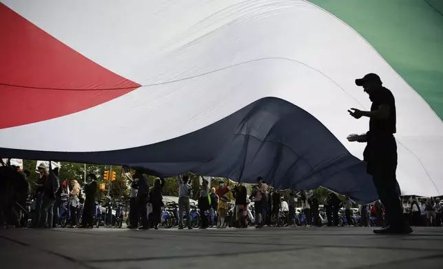 Pro-Palestinian protesters spread a Palestinian flag while demonstrating outside City Hall, Monday, Oct. 7, 2024, in New York. (AP Photo/Stefan Jeremiah)