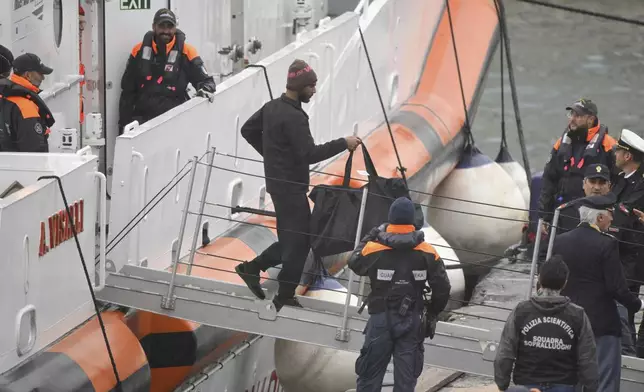 The first 12 migrants that Italy sent to a newly opened asylum processing center in Shengjin, Albania, disembark in the harbor of Bari, in southern Italy, where they are taken back by an Italian Coast Guard ship, Saturday, Oct. 19, 2024, after a court in Rome rejected their detention on Friday, arguing they cannot be sent back to their countries of origin, Bangladesh and Egypt, because the court did not deem them to be safe enough. (AP Photo/Valeria Ferraro)