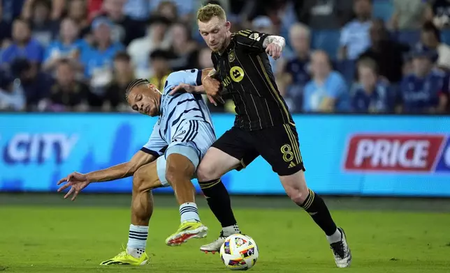 Sporting Kansas City defender Zorhan Bassong, left, and Los Angeles FC midfielder Lewis O'Brien (8) battle for the ball during the first half of an MLS soccer match Saturday, Oct. 5, 2024, in Kansas City, Kan. (AP Photo/Charlie Riedel)