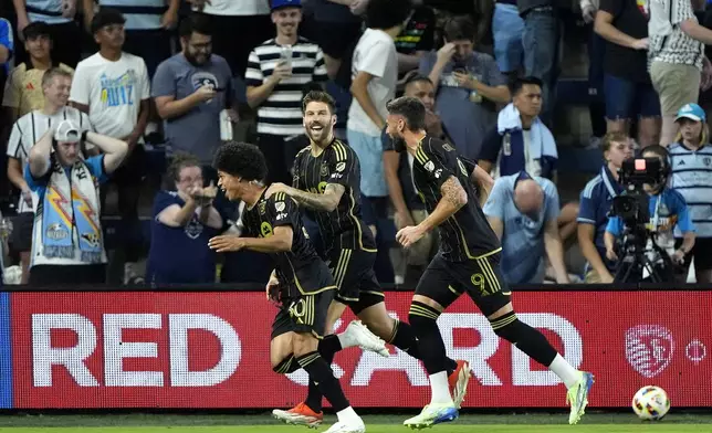 Los Angeles FC attacker David Martínez, left, celebrates with teammates after scoring a goal during the first half of an MLS soccer match against Sporting Kansas City Saturday, Oct. 5, 2024, in Kansas City, Kan. (AP Photo/Charlie Riedel)