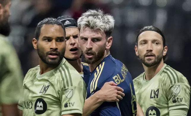 Vancouver Whitecaps' Bjorn Inge Utvik, left, and Tristan Blackmon, right, celebrate Sebastian Berhalter's, not seen, goal against Los Angeles FC during second half MLS soccer action in Vancouver, British Columbia, Sunday, Oct. 13, 2024. (Ethan Cairns/The Canadian Press via AP)