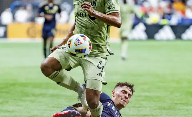 Los Angeles FC's Eddie Segura (4) and Vancouver Whitecaps' Sebastian Berhalter, bottom, vie for the ball during second half MLS soccer action in Vancouver, British Columbia, Sunday, Oct. 13, 2024. (Ethan Cairns/The Canadian Press via AP)