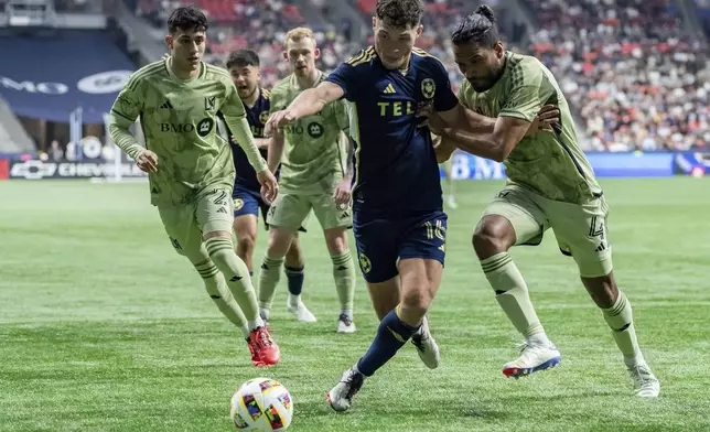 Vancouver Whitecaps' Sebastian Berhalter, center, and Los Angeles FC's Eddie Segura (4) vie for the ball as Los Angeles' Omar Campos (2) watches during second half MLS soccer action in Vancouver, British Columbia, Sunday, Oct. 13, 2024. (Ethan Cairns/The Canadian Press via AP)