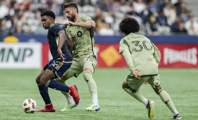 Vancouver Whitecaps' Ralph Priso, left, and Los Angeles FC's Olivier Giroud, center, vie for the ball as David Martinez (30) watches during second half MLS soccer action in Vancouver, British Columbia, Sunday, Oct. 13, 2024. (Ethan Cairns/The Canadian Press via AP)