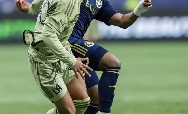 Los Angeles FC's David Martinez, left, and Vancouver Whitecaps' Levonte Johnson, right, vie for the ball during the first half of an MLS soccer match in Vancouver, British Columbia, Sunday, Oct. 13, 2024. (Ethan Cairns/The Canadian Press via AP)