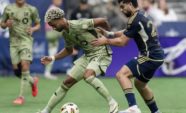 Los Angeles FC's Timothy Tillman, front left, and Vancouver Whitecaps' Brian White, right, vie for the ball during the first half of an MLS soccer match in Vancouver, British Columbia, Sunday, Oct. 13, 2024. (Ethan Cairns/The Canadian Press via AP)