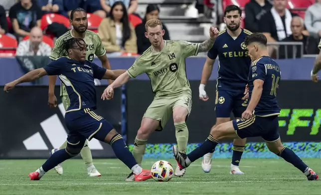 Vancouver Whitecaps' Levonte Johnson, front left, and Sebastian Berhalter, right, vie for the ball with Los Angeles FC's Lewis O'Brien, center, during the first half of an MLS soccer match in Vancouver, British Columbia, Sunday, Oct. 13, 2024. (Ethan Cairns/The Canadian Press via AP)