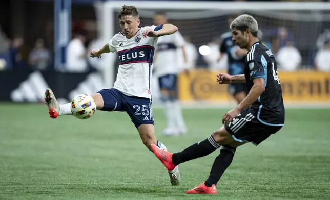 Vancouver Whitecaps' Ryan Gauld (25) blocks Minnesota United's Miguel Tapias, right, during the second half of an MLS soccer game, Saturday, Oct. 5, 2024 in Vancouver, British Columbia. (Ethan Cairns/Canadian Press via AP)