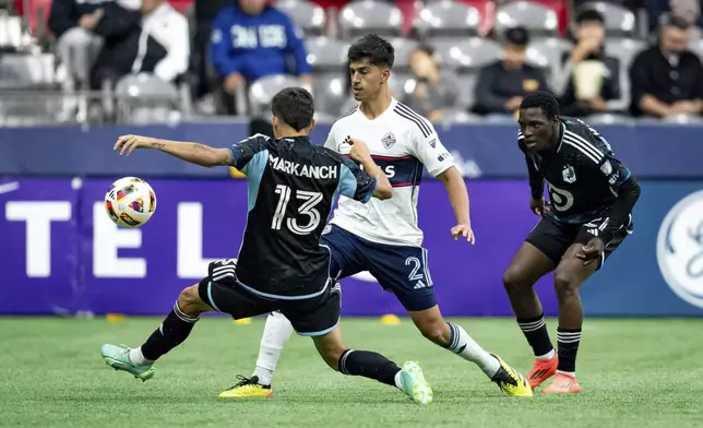 Minnesota United's Anthony Markanich (13) and Vancouver Whitecaps' Mathias Laborda (2) vie for the ball as Minnesota's Bongokuhle Hlongwane, right, watches during the second half of an MLS soccer game, Saturday, Oct. 5, 2024 in Vancouver, British Columbia. (Ethan Cairns/Canadian Press via AP)