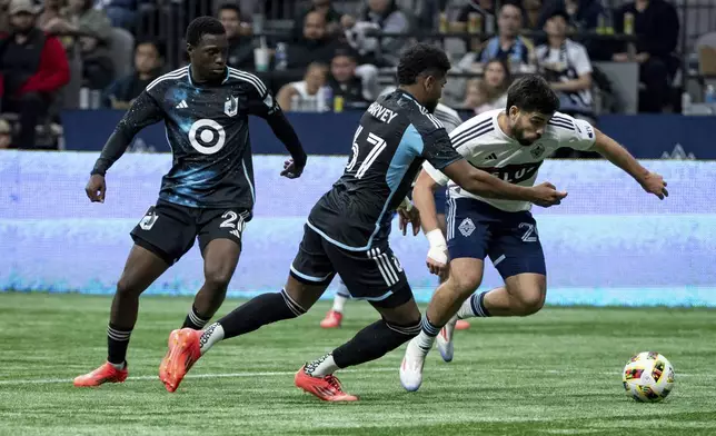 Minnesota United's Carlos Harvey, centre, and Vancouver Whitecaps' Brian White, right, vie for the ball as Minnesota's Bongokuhle Hlongwane, left, watches during the second half of an MLS soccer game, Saturday, Oct. 5, 2024 in Vancouver, British Columbia. (Ethan Cairns/Canadian Press via AP)