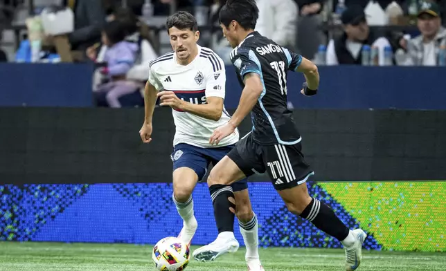 Vancouver Whitecaps' Alessandro Schopf, left, and Minnesota United's Sang-Bin Jeong (11) vie for the ball during the second half of an MLS soccer game, Saturday, Oct. 5, 2024 in Vancouver, British Columbia. (Ethan Cairns/Canadian Press via AP)