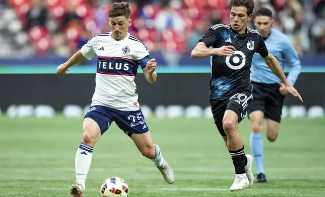 Vancouver Whitecaps' Ryan Gauld (25) and Minnesota United's Will Trapp (20) vie for the ball during the second half of an MLS soccer game, Saturday, Oct. 5, 2024 in Vancouver, British Columbia. (Ethan Cairns/Canadian Press via AP)