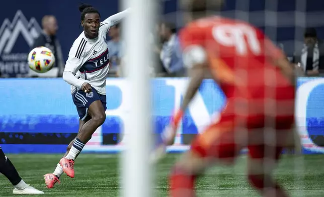 Vancouver Whitecaps' Sam Adekugbe, left, kicks the ball at Minnesota United goalkeeper Dayne St. Clair, right, missing the net during the second half of an MLS soccer game, Saturday, Oct. 5, 2024 in Vancouver, British Columbia. (Ethan Cairns/Canadian Press via AP)