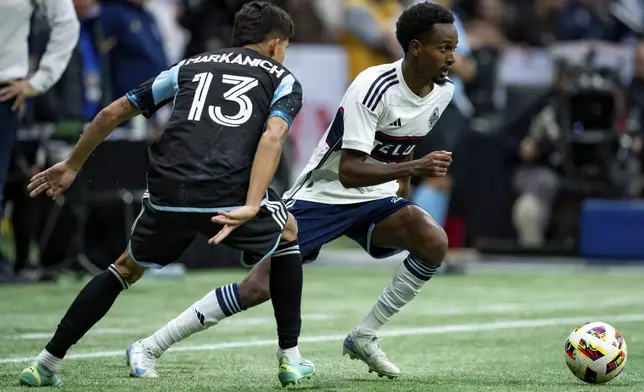 Minnesota United's Anthony Markanich (13) and Vancouver Whitecaps' Ali Ahmed, right, vie for the ball during the second half of an MLS soccer game, Saturday, Oct. 5, 2024 in Vancouver, British Columbia. (Ethan Cairns/Canadian Press via AP)