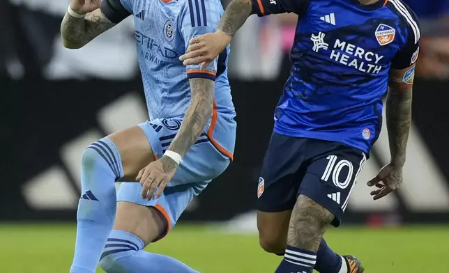 New York City FC defender Birk Risa, left, and FC Cincinnati midfielder Luciano Acosta (10) look at the ball during the second half of a first-round soccer match of the MLS Cup playoffs, Monday, Oct. 28, 2024, in Cincinnati. (AP Photo/Carolyn Kaster)