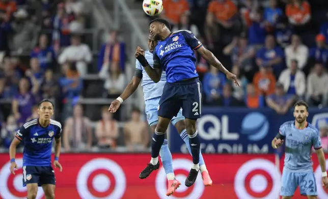 FC Cincinnati defender Alvas Powell (2) goes up for the ball in front of New York City FC midfielder Andrés Perea, center left, during the second half of a first-round soccer match of the MLS Cup playoffs, Monday, Oct. 28, 2024, in Cincinnati. (AP Photo/Carolyn Kaster)