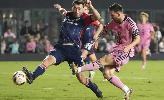 Inter Miami forward Lionel Messi (10) scores a goal as New England Revolution defender Dave Romney, left, defends during the second half of an MLS soccer match, Saturday, Oct. 19, 2024, in Fort Lauderdale, Fla. (AP Photo/Lynne Sladky)