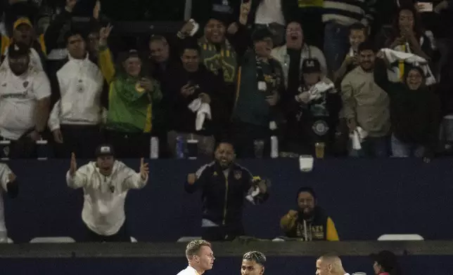 Los Angeles Galaxy defender John Nelson (14) celebrates his goal with midfielder Edwin Cerrillo (20) and forward Dejan Joveljić (9) during the second half of the first match of an MLS Cup playoffs opening round against the Colorado Rapids, Saturday, Oct. 26, 2024, in Carson, Calif. (AP Photo/Kyusung Gong)