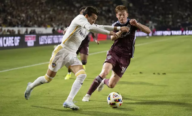 Los Angeles Galaxy midfielder Riqui Puig (10) dribbles as Colorado Rapids midfielder Oliver Larraz (18) defends during the first half of the first match of an MLS Cup playoffs opening round, Saturday, Oct. 26, 2024, in Carson, Calif. (AP Photo/Kyusung Gong)