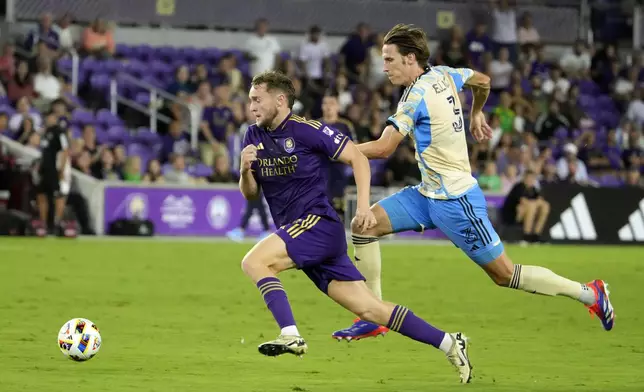 Orlando City's Duncan McGuire, left, gets past Philadelphia Union's Jack Elliott (3) to score a goal during the second half of an MLS soccer match, Wednesday, Oct. 2, 2024, in Orlando, Fla. (AP Photo/John Raoux)