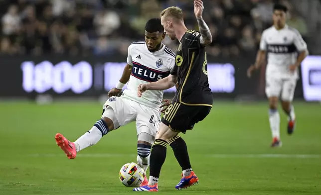 Los Angeles FC midfielder Lewis O'Brien (8) vies for the ball with Vancouver Whitecaps midfielder Pedro Vite, left, during the first half of the first soccer match of an MLS Cup playoffs opening round in Los Angeles, Sunday, Oct. 27, 2024. (AP Photo/Alex Gallardo)